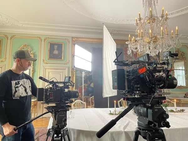 Film cameras and lighting equipment set up in an ornate dining room