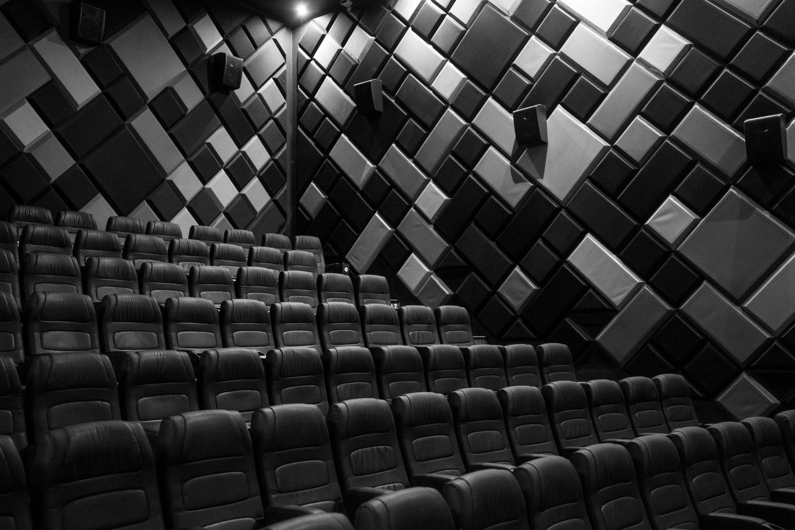 Empty cinema auditorium with geometric acoustic panels and dark seats