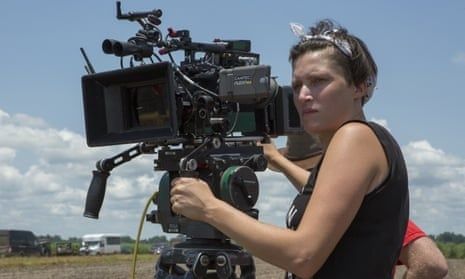 Cinematographer operating a large camera outdoors under a blue sky