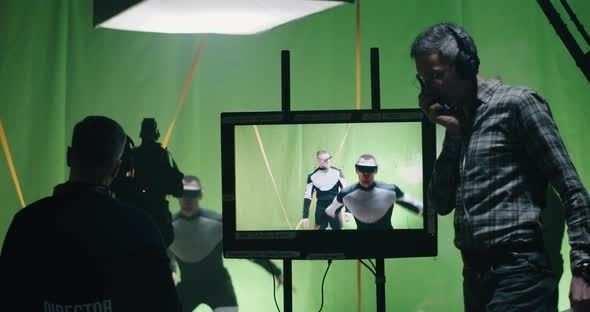 Film crew and director monitor a green-screen scene during production